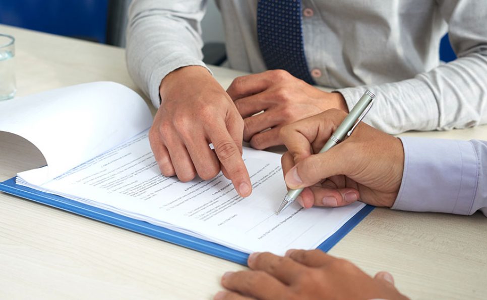 Businessman showing his partner where to sign the contract